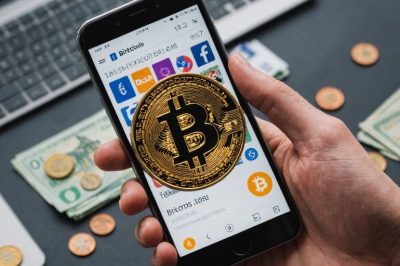 Smartphone mit Bitcoin-Symbol und Euro-Münzen